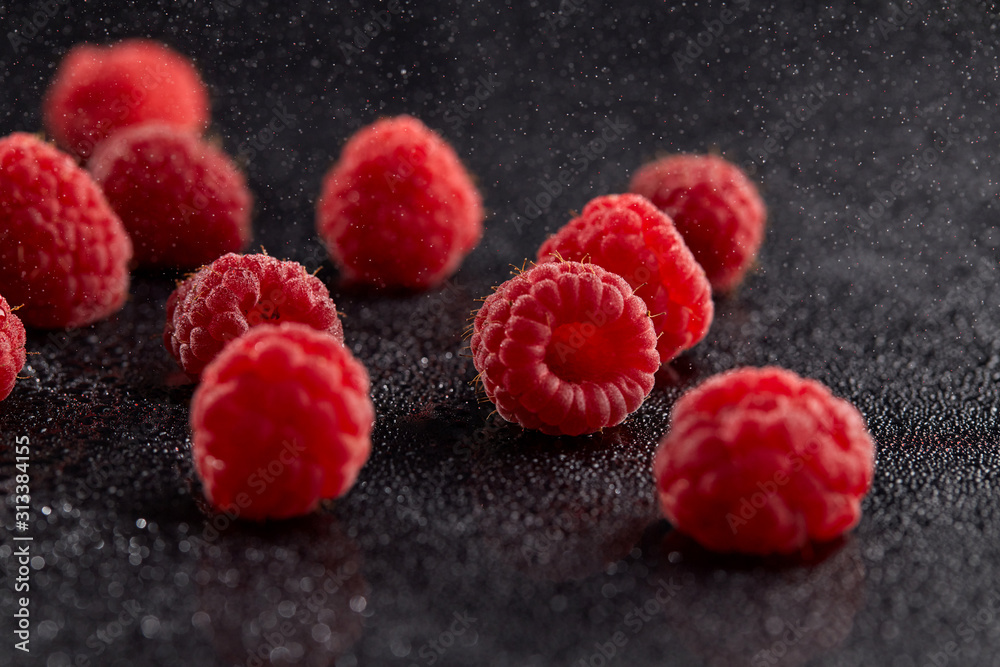 Fresh raspberries in chaotic order on a dark background with water droplets and shadows. Fresh raspberries in chaotic order on a dark background with water droplets and shadows.