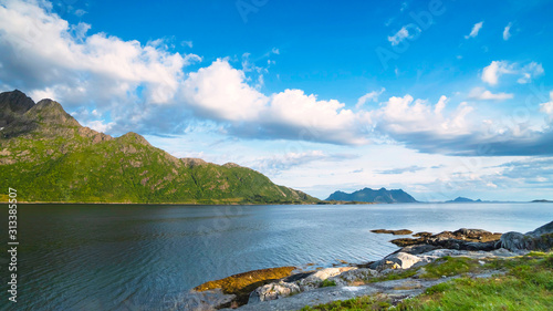 Summer sunny landscape of Lofoten islands, Norway. Fjord surrounded by green hills, rocky shore.
