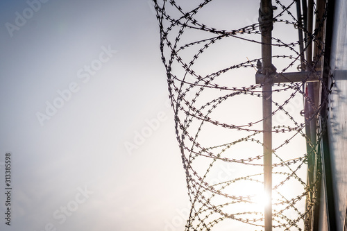 barbed wire against blue sky with sun