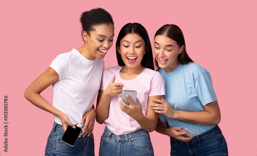 Three Girls Using Smartphone Recommending Application To Friends, Pink Background Three Girls Using Smartphone Recommending Application To Friends, Pink Background