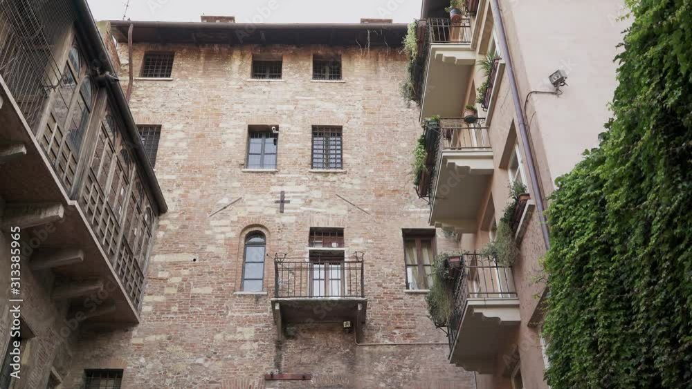 Tilt up gimbal shot of old ancient european building and green ivy on the walls. Tilt up of stone old building in Europe during summer day Tilt up gimbal shot of old ancient european building and green ivy on the walls. Tilt up of stone old building in Europe during summer day