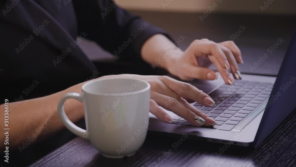 American woman work in the office front laptop screen with hand. Female in black is at table with coffee in room. American woman work in the office front laptop screen with hand. Female in black is at table with coffee in room.
