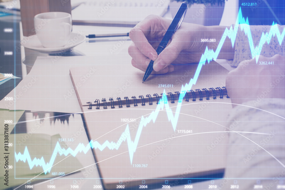 Forex chart hologram on hand taking notes background. Concept of analysis. Double exposure Forex chart hologram on hand taking notes background. Concept of analysis. Double exposure