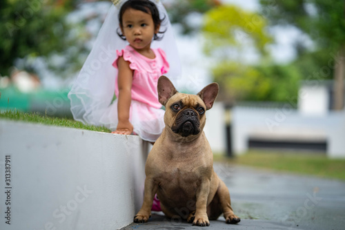 Cute asian girl playing with her lovely french bulldog at marble seat in park. © tienuskin