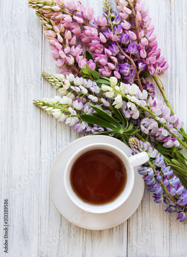 Pink and purple lupine flowers and cup of tea