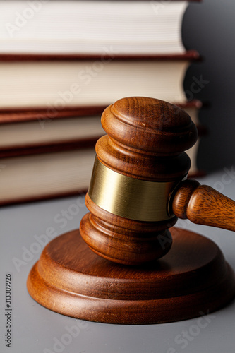 Brown wooden gavel with stack of books on gray table