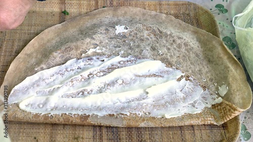 Woman hand spreading a Pita bread with Druz Labaneh cream cheese.
