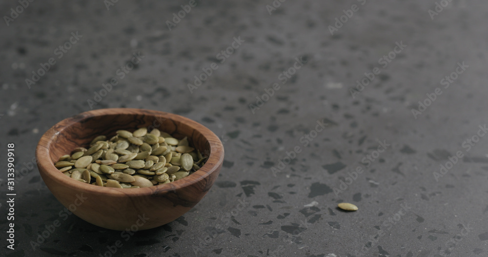 pumpkin seeds in olive bowl on terrazzo countertop with copy space pumpkin seeds in olive bowl on terrazzo countertop with copy space