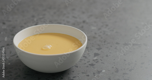 pumpkin cream soup in white bowl on terrazzo countertop