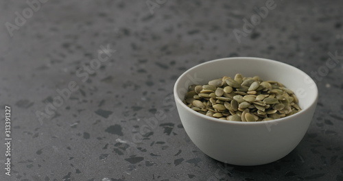 pumpkin seeds in white bowl on terrazzo countertop with copy space