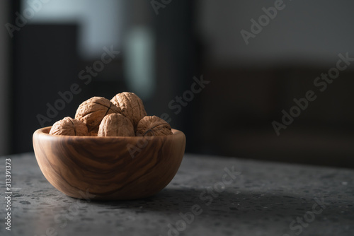 inshell walnuts in olive wood bowl on terrazzo countertop