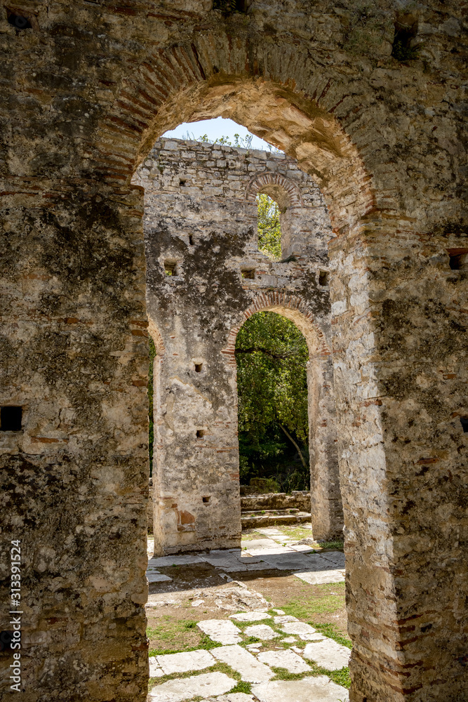 Church arcs, framed view. Beautiful warm spring day and archeological ruins at Butrint National Park, Albania, UNESCO heritage. Travel photography with fresh green flora and clear blue sky