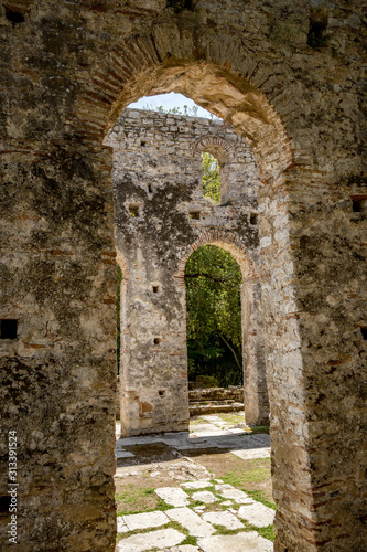 Church arcs  framed view. Beautiful warm spring day and archeological ruins at Butrint National Park  Albania  UNESCO heritage. Travel photography with fresh green flora and clear blue sky