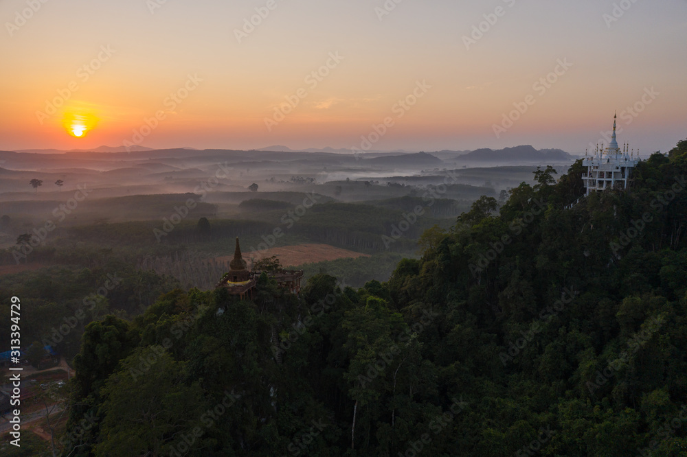 Beautiful sunrise with pagoda on the top of rock and tree with fog at Khao Na Nai Luang Dharma Park,Surat thani province,Thailand