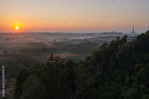 Beautiful sunrise with pagoda on the top of rock and tree with fog at Khao Na Nai Luang Dharma Park Surat thani province Thailand