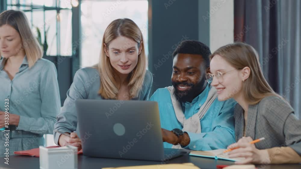 Young happy multi-ethnic co-workers gathered together working discuss current issues smiling common tasks african team leader talk with colleague business workplace skilled technology strategy. Slow