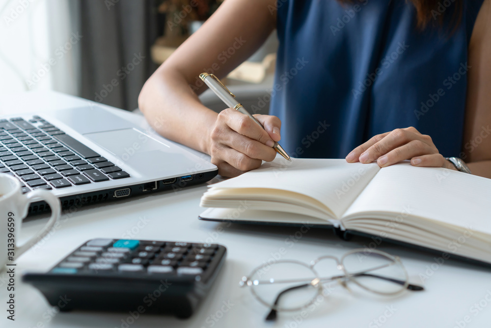 Beautiful young smiling Asian businesswoman writing notebook document finance and calculator at home office. Beautiful young smiling Asian businesswoman writing notebook document finance and calculator at home office.