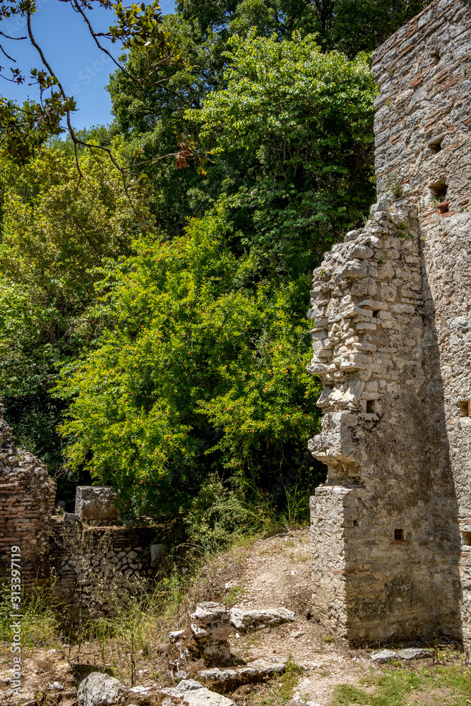 Church ruined walls. Beautiful warm spring day and archeological ruins at Butrint National Park, Albania, UNESCO heritage. Travel photography with fresh green flora and clear blue sky