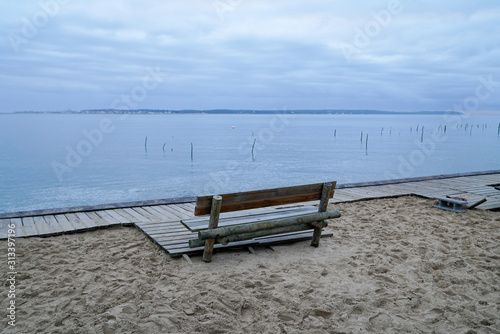 wooden winter bench view over Arcachon Bay basin in France near Cap Ferret with Dune du Pilat Pyla background in sunrise © OceanProd