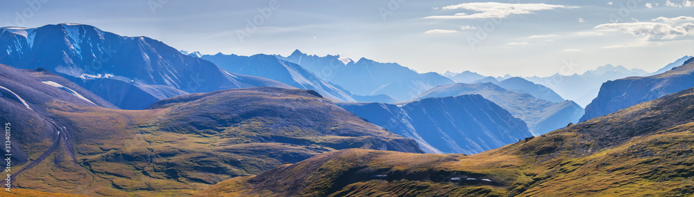 Panoramic view, mountain landscape. Treeless hills, peaks in a blue haze. Travel and vacation in the mountains.