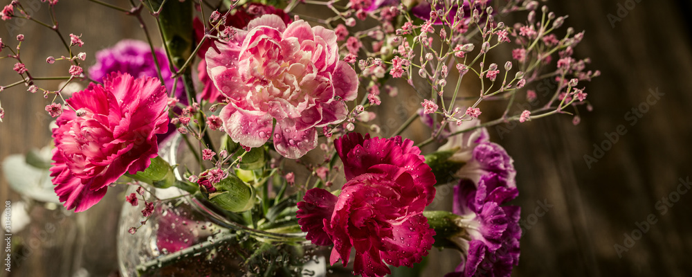 Φωτογραφία Bouquet of pink carnation in glass vase on old wooden background