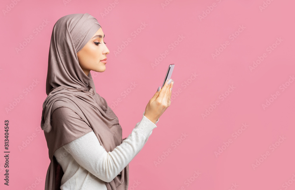 Profile portrait of serious islamic woman with smartphone in hands