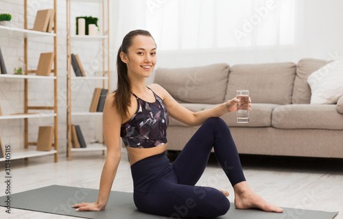 Fit woman resting after home workout and drinking water