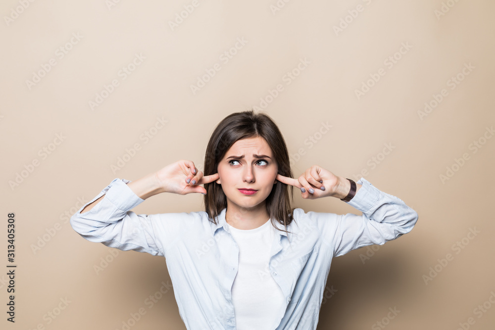Young pretty woman cover ears isolated on beige background Young pretty woman cover ears isolated on beige background