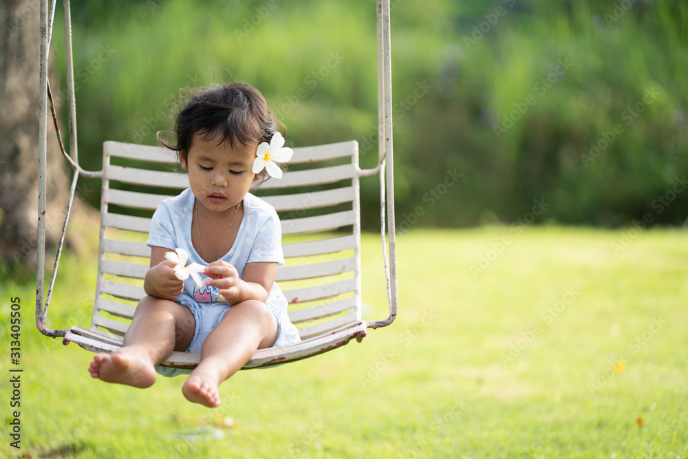 Cute little girl sitting on swing in morning at park. Cute little girl sitting on swing in morning at park.