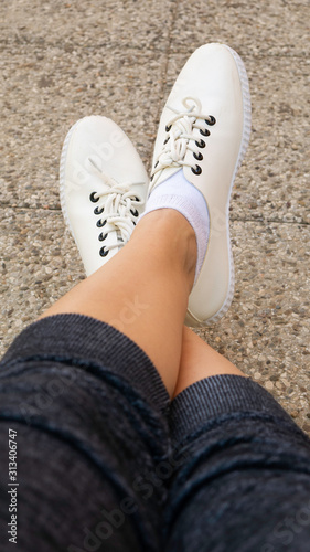 Women feet wearing white fashion sneaker shoes.