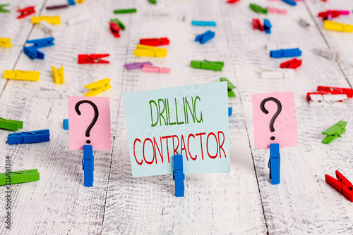 Text sign showing Drilling Contractor. Business photo showcasing contract their services mainly for drilling wells Scribbled and crumbling sheet with paper clips placed on the wooden table photo