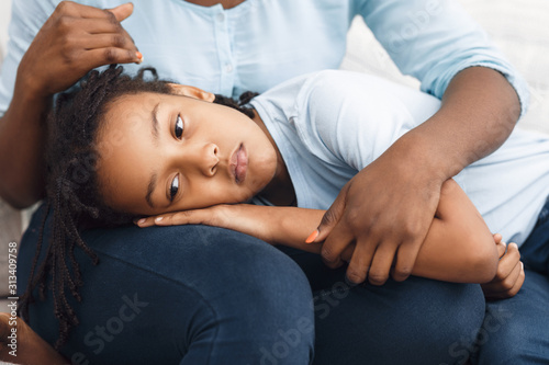 Black daughter lying her head on mom's lap