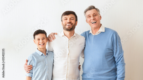 Man, Son And Elderly Father Embracing Standing Over White Wall