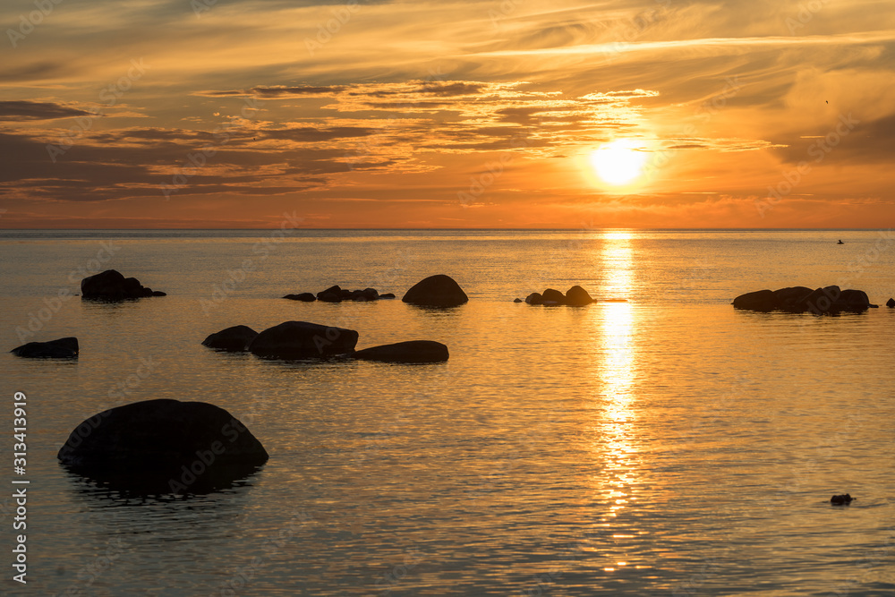 Evening sunlight on coast, yellow clouds, golden sky reflection on water.  Beach in summer. Seaside natural environment. Shore in Harilaid, small  island in Estonia. Nature Reserve in North Europe foto de Stock