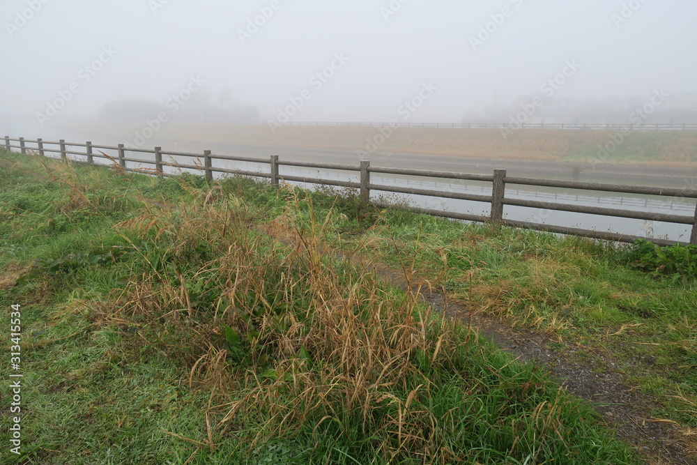 冬の朝霧の放水路土手風景