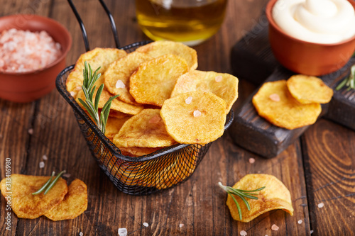 Crispy potato chips. Slices of potato, roasted with sea salt and rosemary. Delicious snack served with sauce. Fast food.