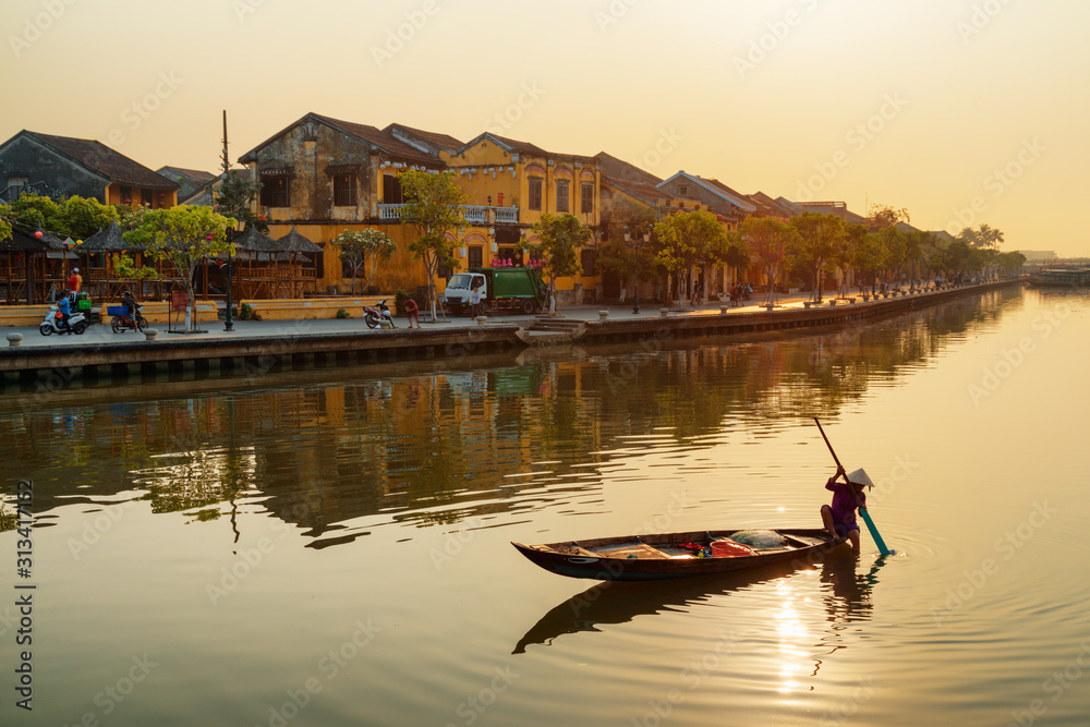 Vietnamese woman in traditional hat on boat at sunrise, Hoian