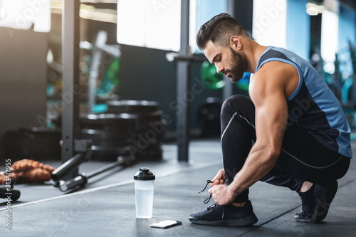 Young athlete tying sneakers laces at gym photo