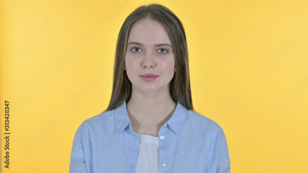 Casual Young Woman putting Finger on Lips, Yellow Background