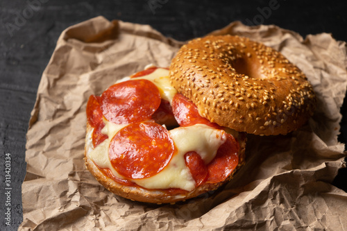 Sesame bagels with pepperoni and cheese on dark background