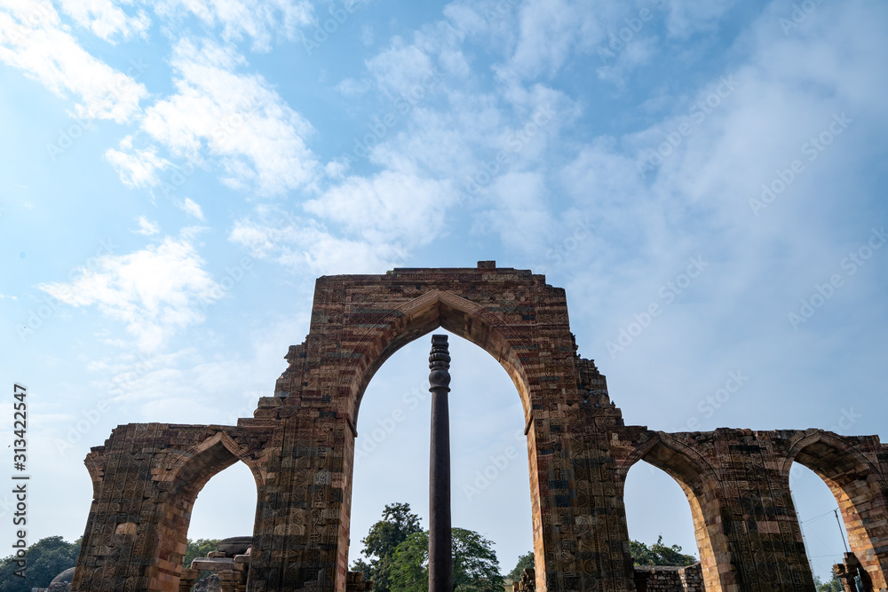 Famous iron pillar frame with ruins at the Qutub Minar complex in New Delhi India. Negative space composition, with extra copy space