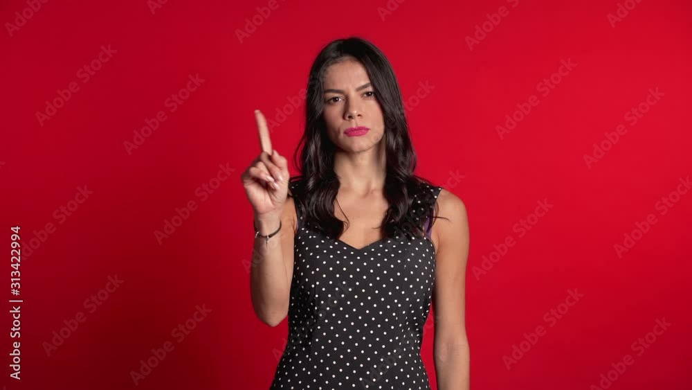 Hispanic girl disapproving with no hand sign make negation finger gesture. Denying, Rejecting, Disagree, Portrait of pretty woman on red background Hispanic girl disapproving with no hand sign make negation finger gesture. Denying, Rejecting, Disagree, Portrait of pretty woman on red background