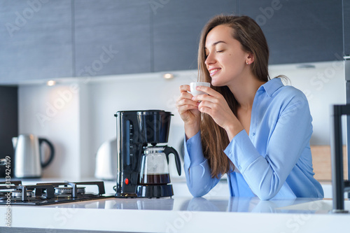 Print op canvas Happy attractive female enjoying of fresh coffee aroma after brewing coffee using coffee maker in the kitchen at home