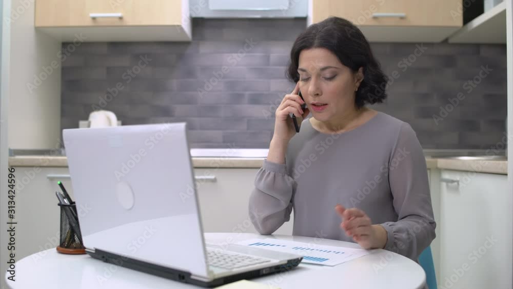 Strict business lady talking on phone, sitting at table, angry boss, stress Strict business lady talking on phone, sitting at table, angry boss, stress