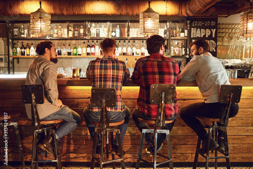 Rear view friends sitting on chairs talking at the bar in a bar. photo