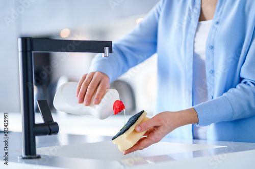 Housewife uses dishwashing detergent for wash up dishes in the kitchen at home photo
