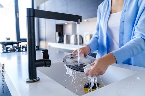 Cleaning woman dishwashing during housework photo