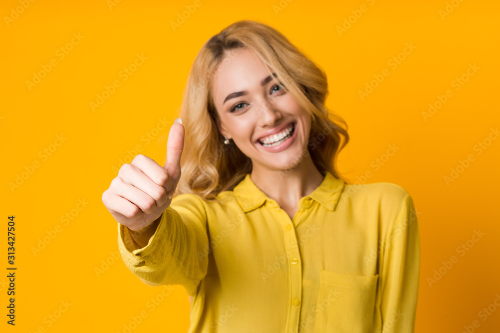 I like it. Woman gesturing thumb up, yellow background