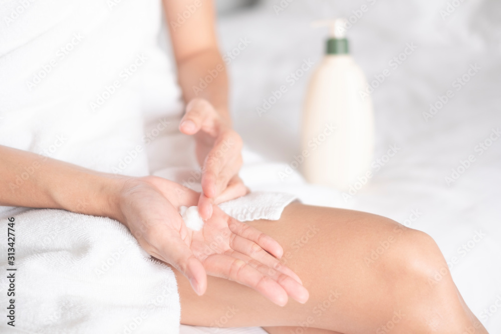 Fototapeta premium Woman applying moisturizing cream/lotion on hands on white bed, beauty concept...