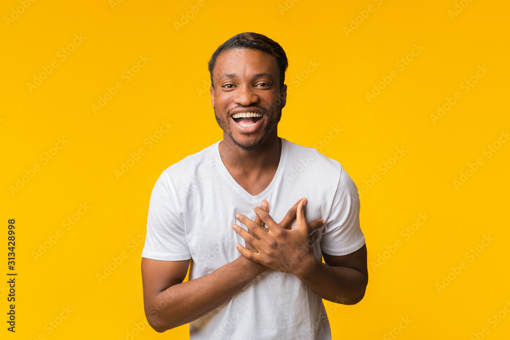 African American Man Laughing Touching Chest Standing Over Yellow Background - obrazy, fototapety, plakaty 